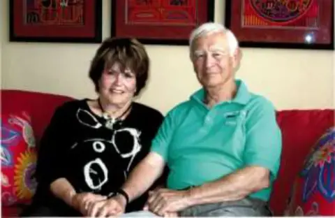A smiling couple seated on a red couch