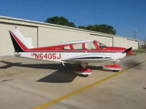 A red and white low-wing airplane on the ramp