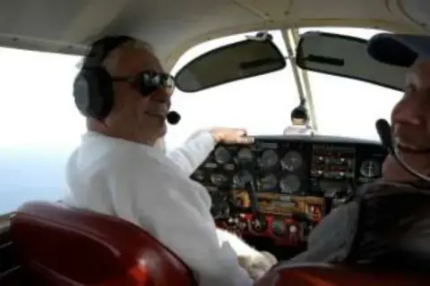 A pilot in a headset at the controls of a small airplane
