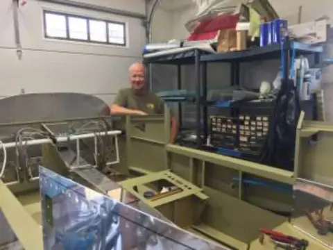A man working on an airplane fuselage in a home workshop