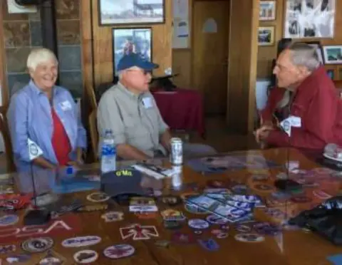 Members at a table covered with patches and pins