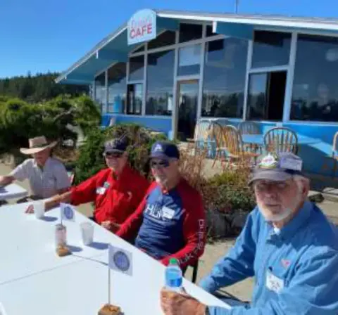 Members at an outdoor table in front of a cafe