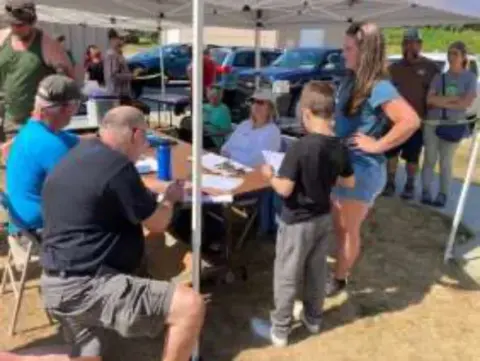 Volunteers and young people at a registration table under a tent