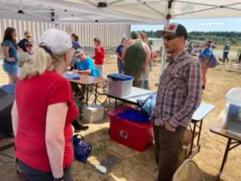 Volunteers and families under a canopy at a Young Eagles rally