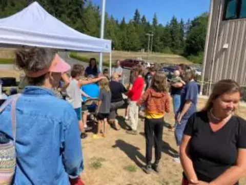 A crowd gathered by canopies and hangars at a Young Eagles rally