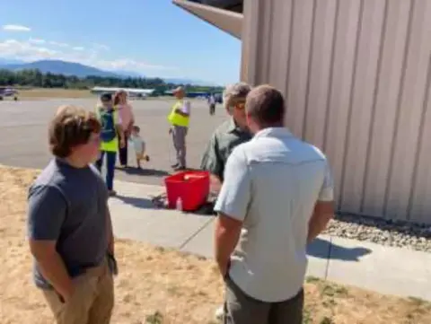 People talking beside a hangar at a Young Eagles rally