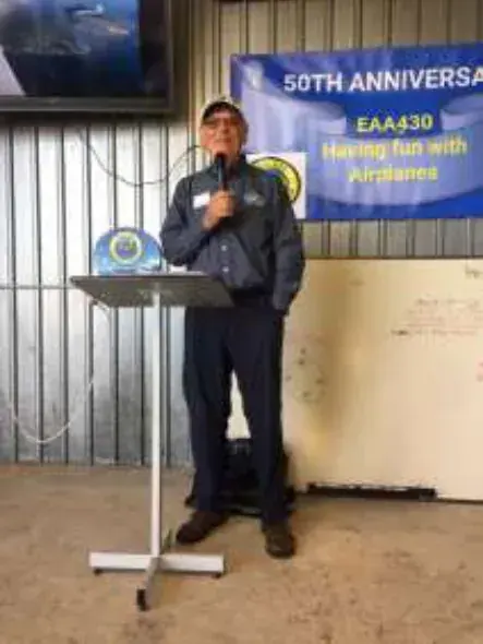 A speaker at a podium in front of a 50th anniversary banner
