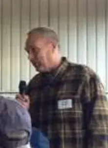 A man in a plaid shirt speaking into a microphone