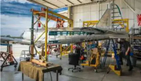 An airplane on a maintenance stand in a busy hangar
