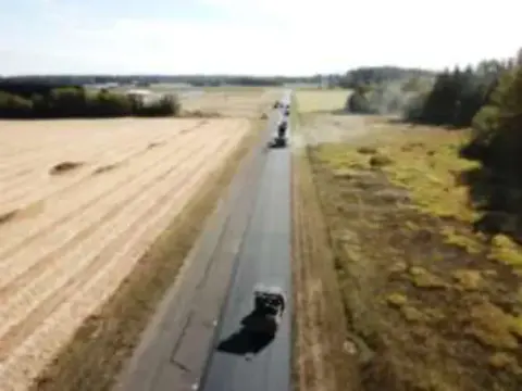 Aerial view of a freshly paved runway between fields