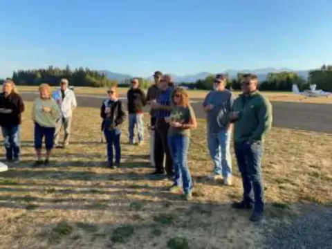 A group of members standing on the airfield at sunrise