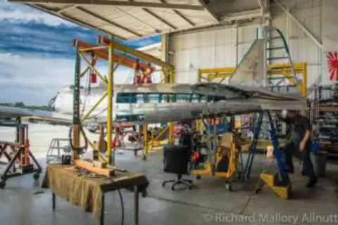 An airplane on a work stand in a busy hangar