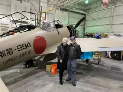 A couple standing by a Japanese World War II fighter in a museum