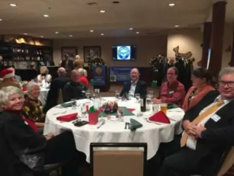 Members seated at round tables in a banquet room at the Christmas party