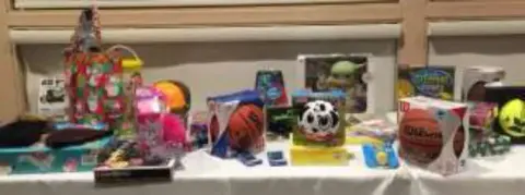 A table of wrapped gifts and toys, including balls and games