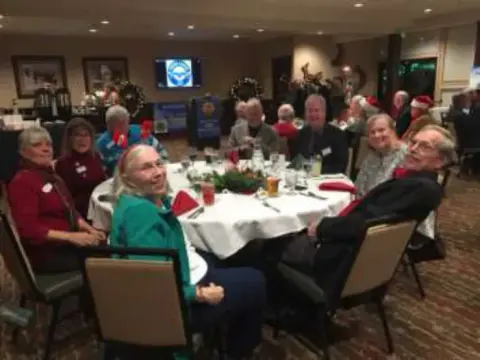 Members at round tables decorated with red napkins