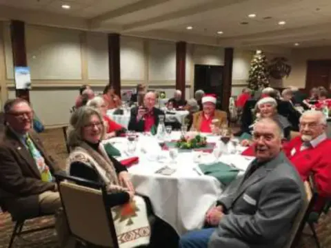 Members at a table near a Christmas tree