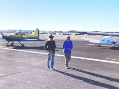 Two people walking across the ramp toward parked airplanes
