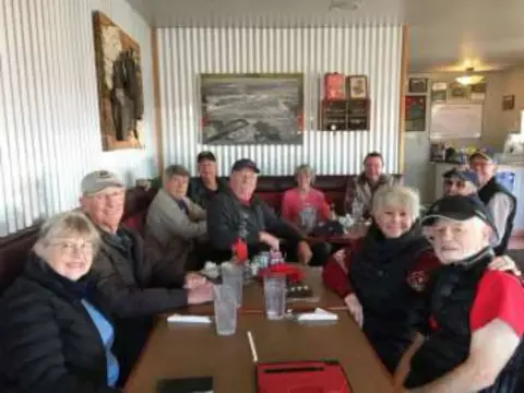 Members seated at a restaurant table with framed pictures on the wall