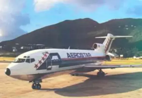 A white jetliner on the ramp with mountains behind