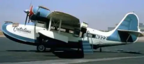 A white and blue amphibious airliner on the ramp