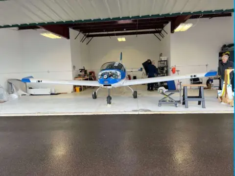 The club airplane with its wings on in the hangar