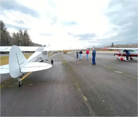 A white airplane on the ramp with others in the distance