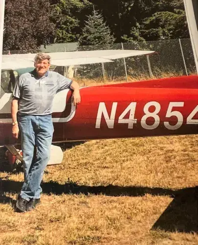 A man standing beside a red airplane