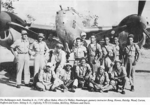 A black and white group photo of a World War II bomber crew in front of their airplane