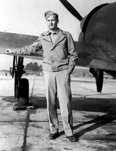 An old photo of a pilot standing in front of a fighter