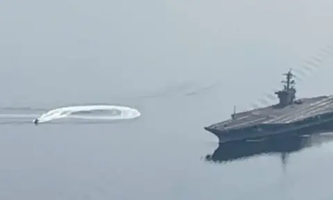 An aircraft carrier making a wake on the water