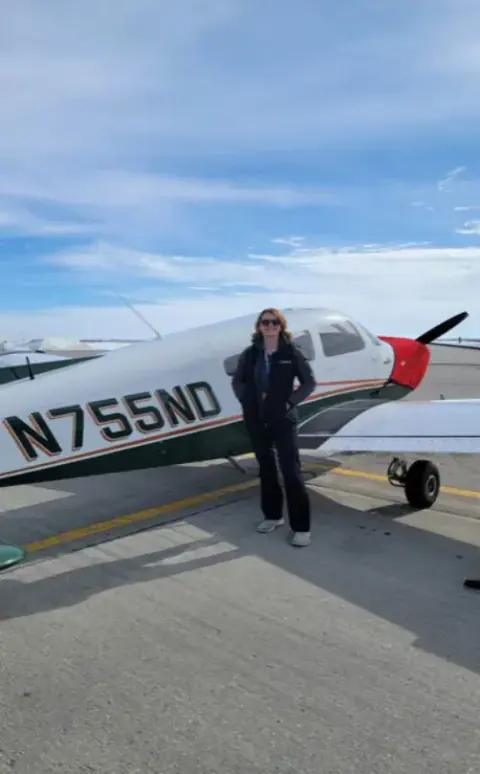 A pilot standing beside a white airplane on the ramp