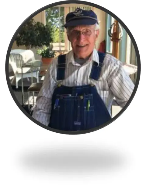 A circular portrait of an older man in overalls and a cap
