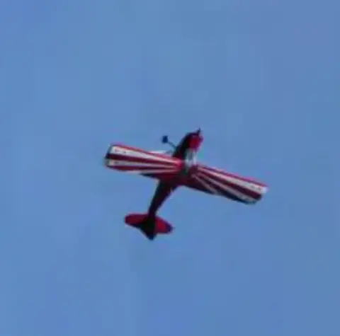 A red and white aerobatic airplane flying upside down
