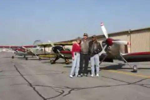 Three people standing in front of a row of parked airplanes