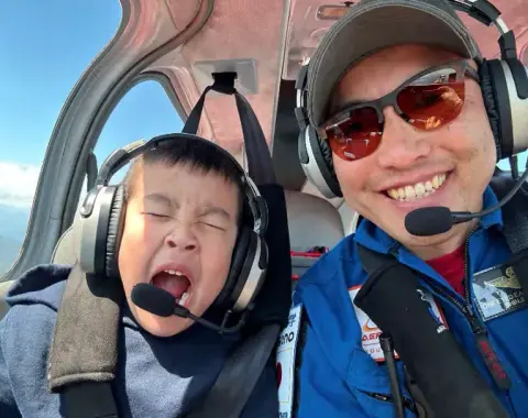 A boy and a pilot in headsets in a cockpit