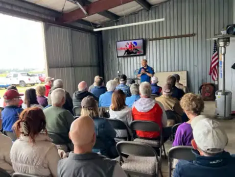 Members seated for the general meeting in a hangar
