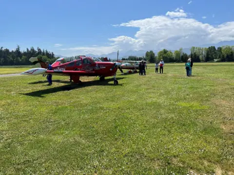 A red jet on the grass with spectators nearby