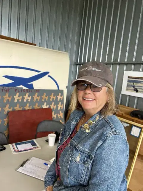 A woman in a cap and denim jacket standing in an office