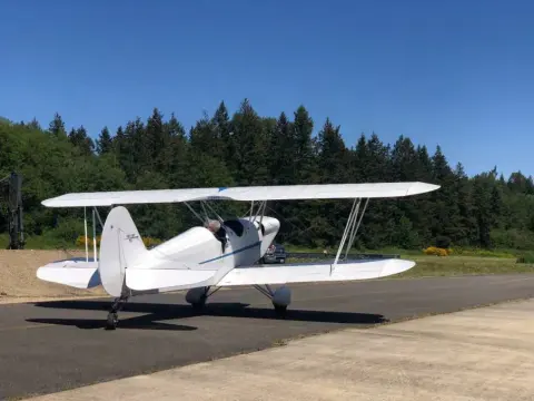 A white Stearman biplane on the ramp