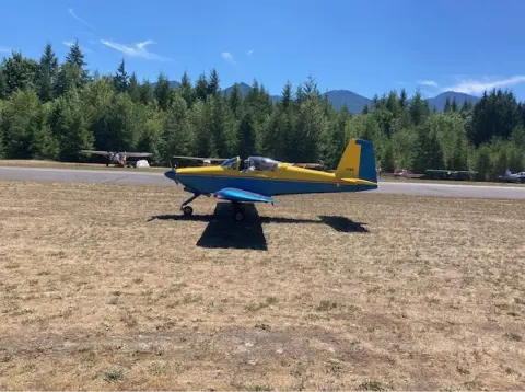 A yellow and blue low-wing airplane parked on the grass