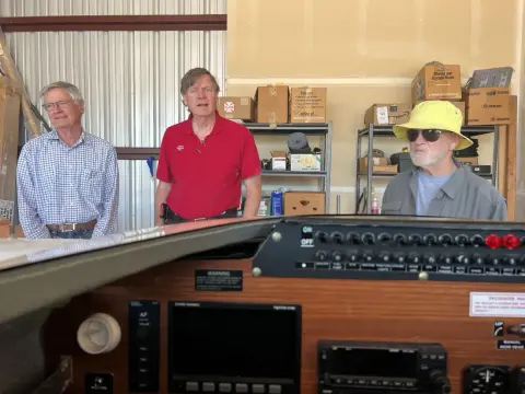 Three people at a workbench with radio equipment