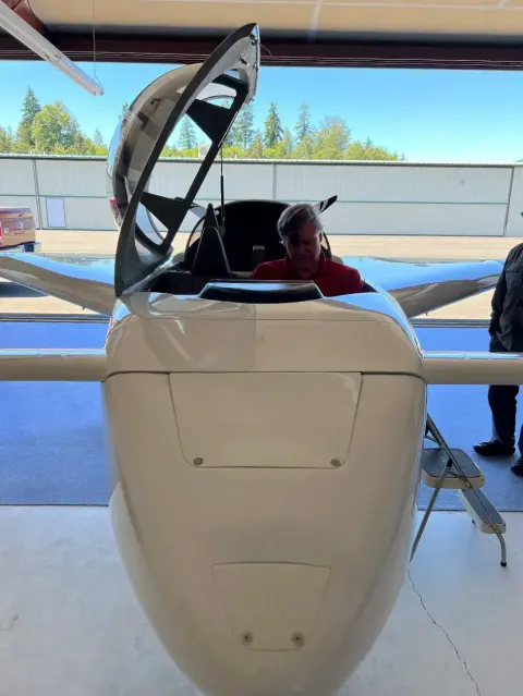 The nose of a white composite airplane with its canopy open