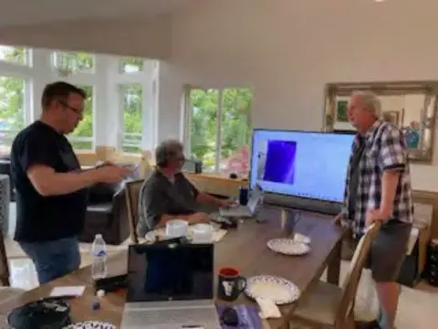 Members gathered around a computer at the workshop
