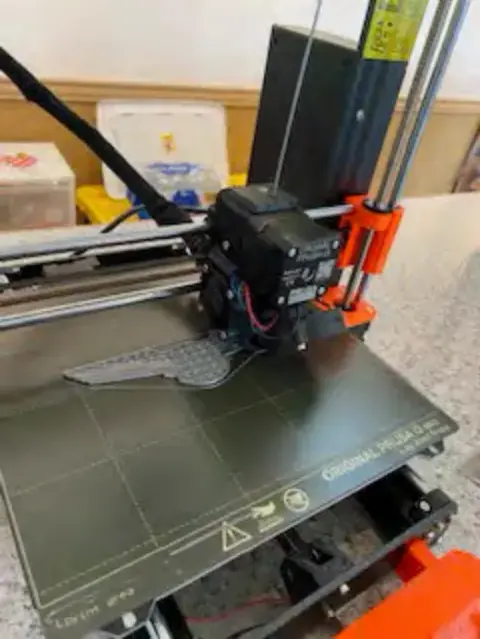 A 3D printer at work with orange frame parts