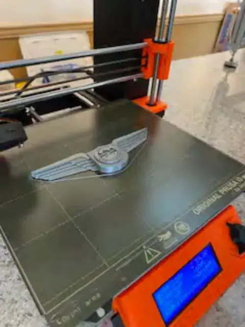 A 3D printer printing a wings badge