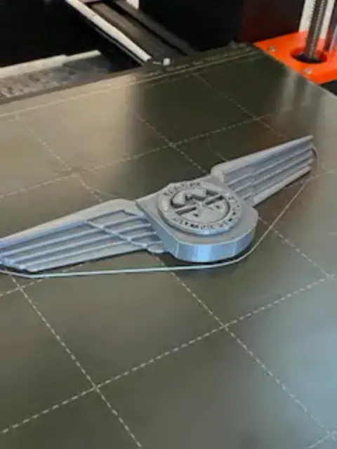 A close-up of a wings badge on the printer bed