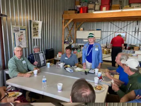 Members seated at tables in a hangar during the poker run