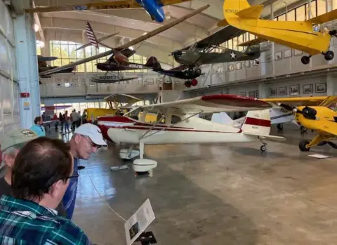 Visitors among historic airplanes inside a museum hangar
