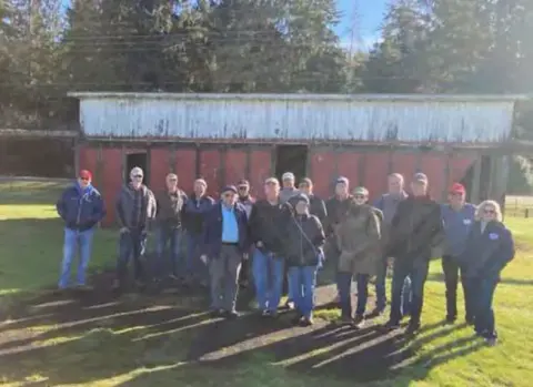 A group of members in front of a red barn